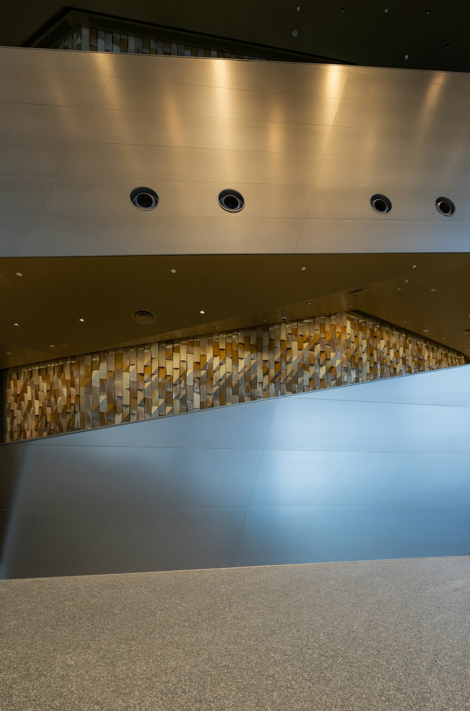 Moderne Innenwand mit geometrischen Paneelen über einem gesprenkelten Boden.